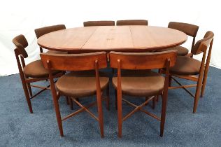 G PLAN TEAK DINING TABLE AND CHAIRS with a pull apart top revealing a fold out leaf, standing on