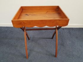 TEAK BUTLERS TRAY with a shaped frieze and side carry handles, on a folding stand, 74.5cm x 58.5cm x