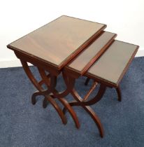 NEST OF WALNUT OCCASIONAL TABLES with rectangular inset glass tops, standing on crossover