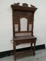 EDWARDIAN OAK HALL STAND with a shaped carved top rail above carved panels with a central arched