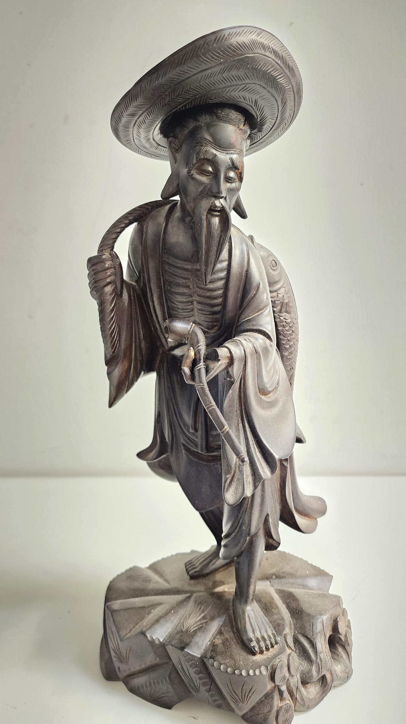EARLY 20th CENTURY CHINESE CARVED WOOD FIGURE depicting a fisherman with a fish being carried on his - Image 2 of 2