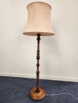 CARVED STANDARD LAMP raised on a circular base with a turned column and pale pink shaped shade,