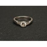 DIAMOND SOLITAIRE RING the central round brilliant cut diamond approximately 0.6cts flanked by two