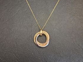 NINE CARAT THREE TONE GOLD PENDANT in the form of an entwined Russian wedding ring, the white gold