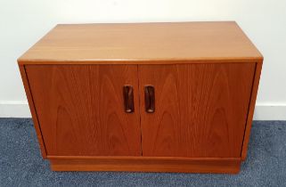 TEAK LOW SIDE CABINET with a pair of doors opening to reveal a shelf, standing on a plinth base,