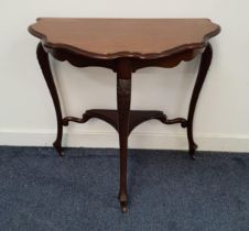 MAHOGANY SIDE TABLE with a shaped top standing on three carved and shaped supports united by an