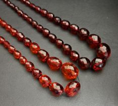 TWO FACETED AMBER COLOURED BEAD NECKLACES the largest bead on each approximately 26mm long, one