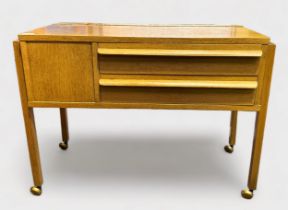 A 1960s oak laminate sewing table, of rectangular form on trestle supports, with piano-hinged top