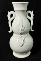 A Chinese Blanc De Chine or Dehua porcelain twin-handled vase, of bulbous double-gourd form, applied