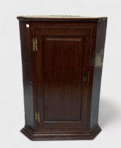 A George III stained oak hanging corner cupboard, with single-door and raised-and-fielded panel