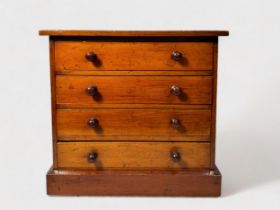 An early 20th century stained walnut table-top collectors chest of four drawers with slide-in