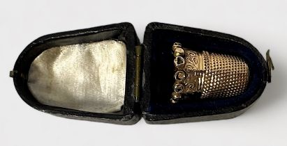 A late Victorian gold thimble, of typical form with dimpled crown and skirt, the lower frieze chased