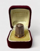 A Late Victorian 9ct gold thimble, of typical dimpled form with harrow horizontal band at the