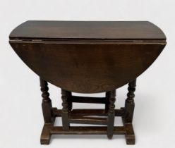A late 19th/early 20th Century stained oak oval drop-leaf occasional table, gate-leg action base,