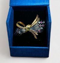 A 14ct yellow and white gold brooch of tied-bow design, claw-set with four rubies and three