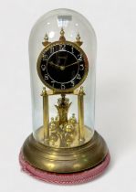 A brass anniversary clock by Violeta, with Arabic numerals to black dial, under brass dome with