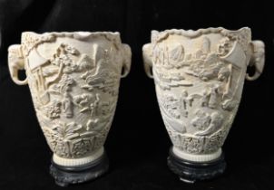 A pair of Chinese two-handled resin vases, each decorated in relief with figures in a landscape with