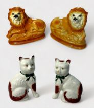 Two pairs of Victorian Staffordshire pottery mantel figures, including recumbent lions with glass