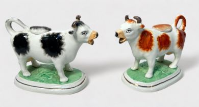 A pair of 19th century pottery cow creamers, with removable covers, raised on naturalistic oval