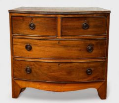 A late Georgian mahogany bow-front chest of two short and two long drawers, with circular brass