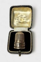 A Victorian 9ct gold thimble, of typical form with dimpled cron and skirt, the lower frieze with a