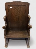 An early 20th Century stained oak settle, single panel back, chamfered sides with shaped armrests,