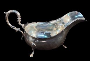 An Edwardian silver sauce boat of oval bellied form with scrolled handle raised on pad feet,