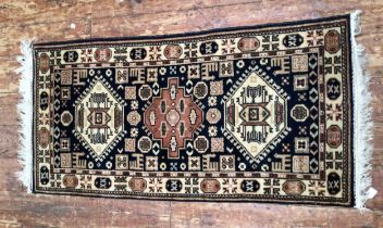 A hand-knotted Caucasian wool fringed rug, with three cental guls to a black ground within a