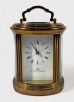 A Swiss made brass-cased oval carriage clock, white enamel dial with Roman numerals inscribed