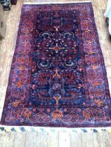 A hand-knotted Caucasian style woolen rug, worked with stylzed foliate field to a deep blue ground