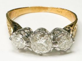 An 18ct yellow gold ring, claw set with three round brilliant cut diamonds, centre stone estimated