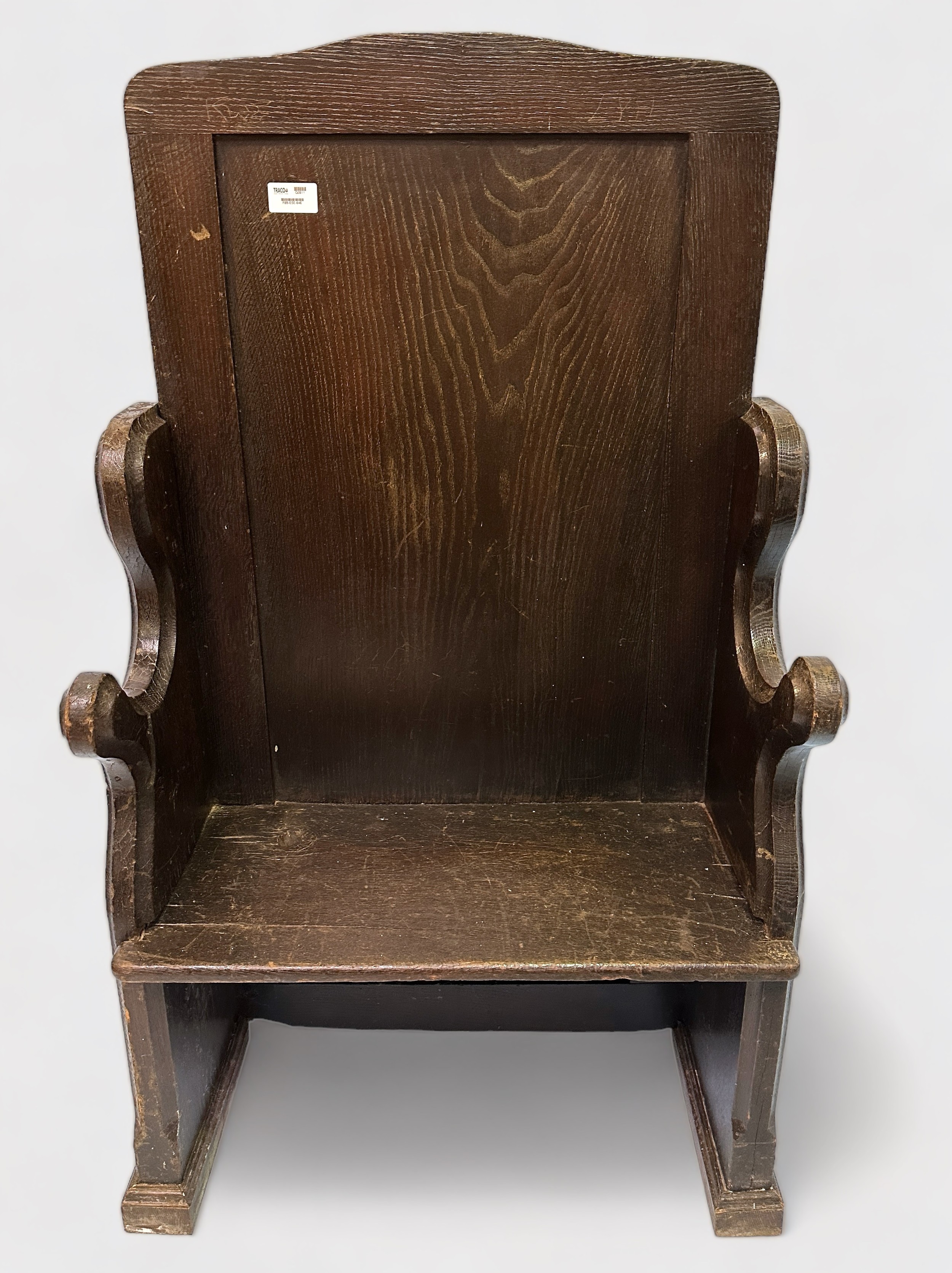 An early 20th Century stained oak settle, single panel back, chamfered sides with shaped armrests,