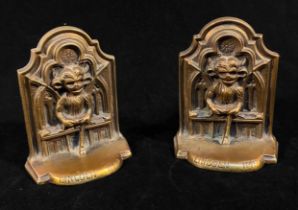 A pair of brass Lincoln Imp bookends, each cast with the Imp in front of a gothic tracery window,