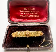 A 15ct yellow gold bar brooch, star-set with a small faceted ruby to the centre of shield,