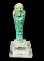 An Egyptian turquoise glazed pottery Shabti figure, raised on stepped clear acrylic base, 9cm tall