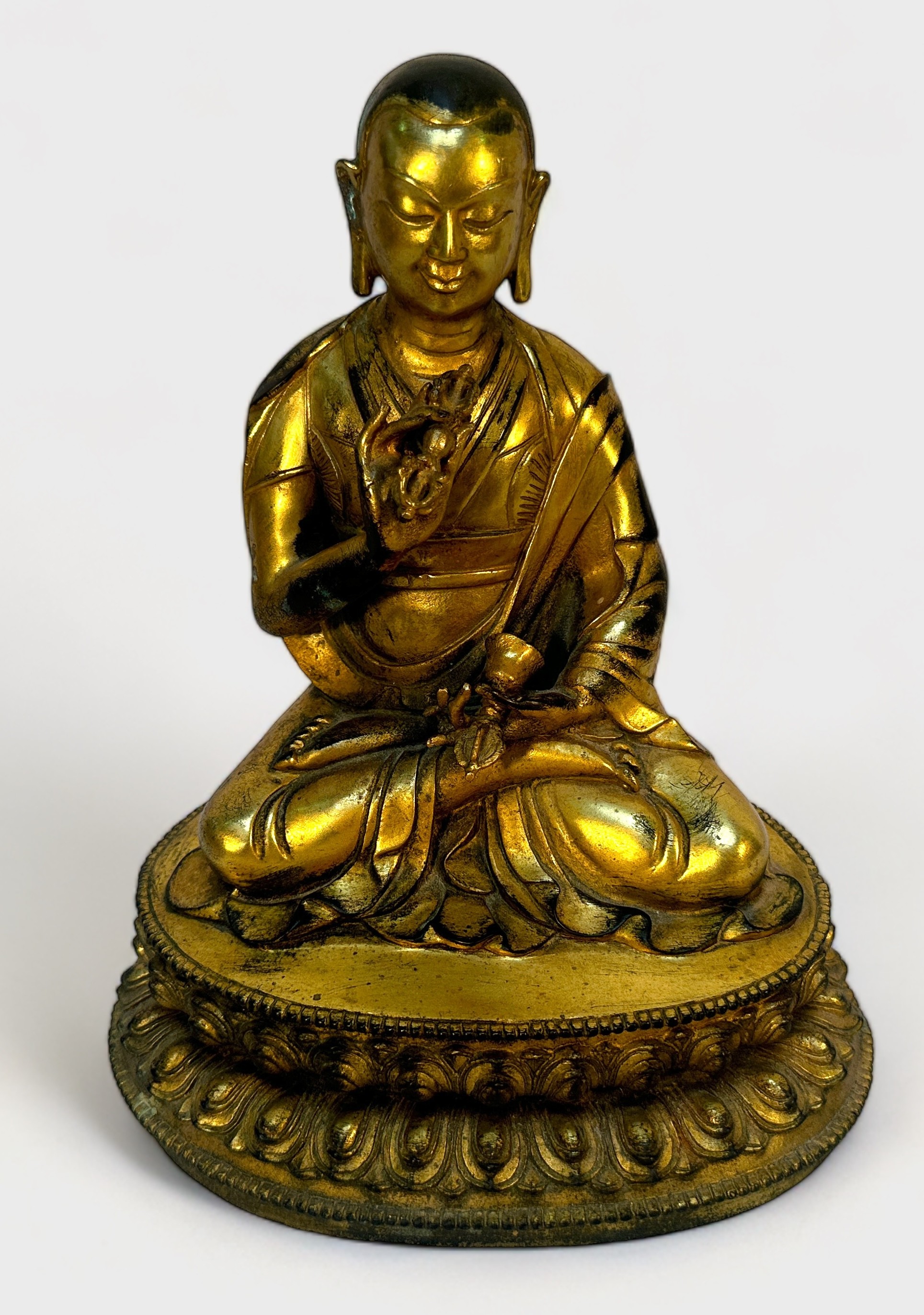 A Gilt-bronze Tibetan style Buddha, seated in lotus position and holding a vajra and meditiation