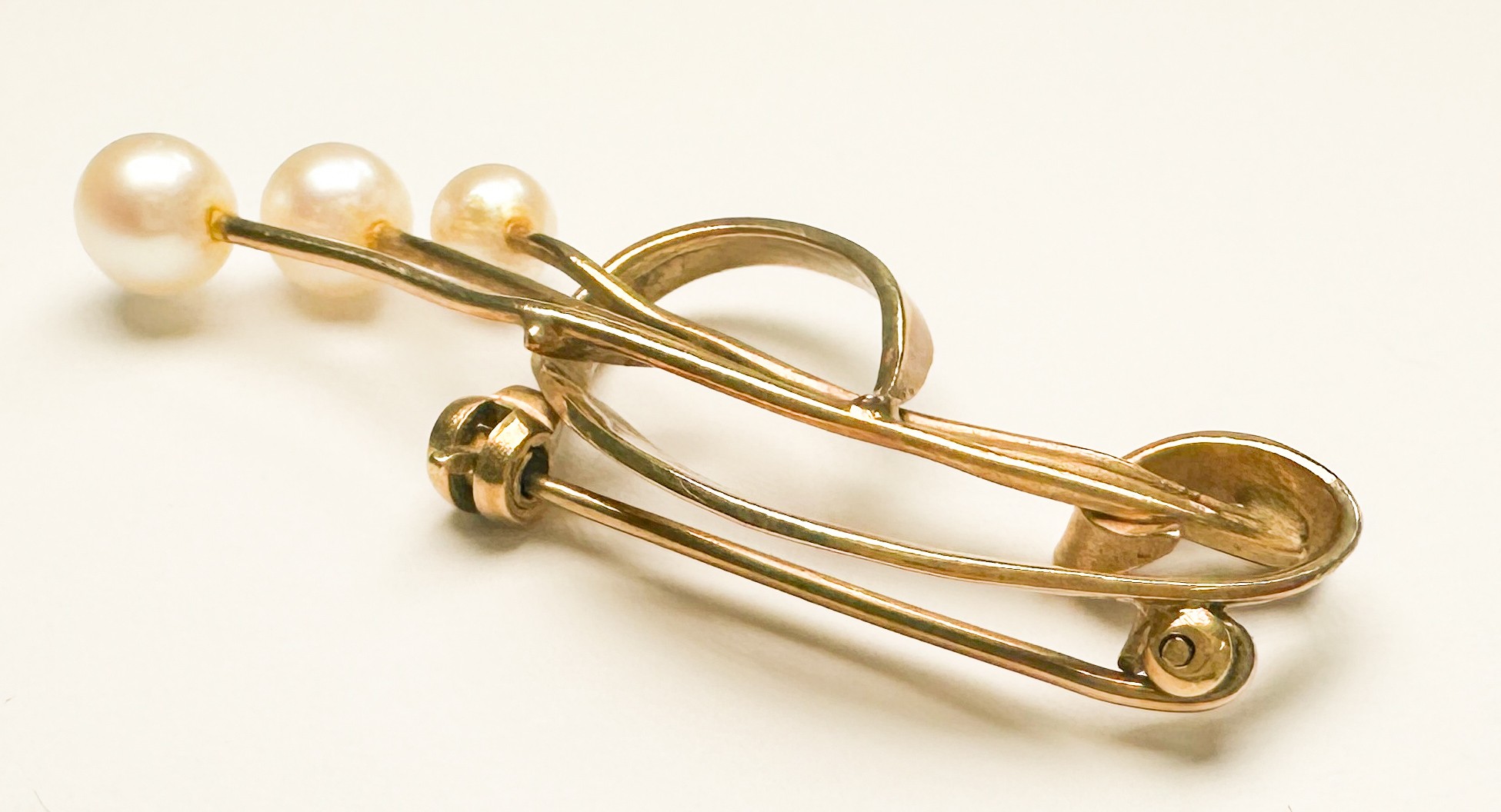 A 9ct gold brooch with three cultured pearls in an open spray design, weighs 3.6 grams.