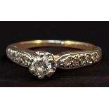 A 14ct gold and diamond ring, centrally claw set with a round brilliant cut diamond, flanked by