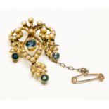 An Edwardian 15ct yellow gold brooch/pendant, set with a central sapphire within an openwork seed