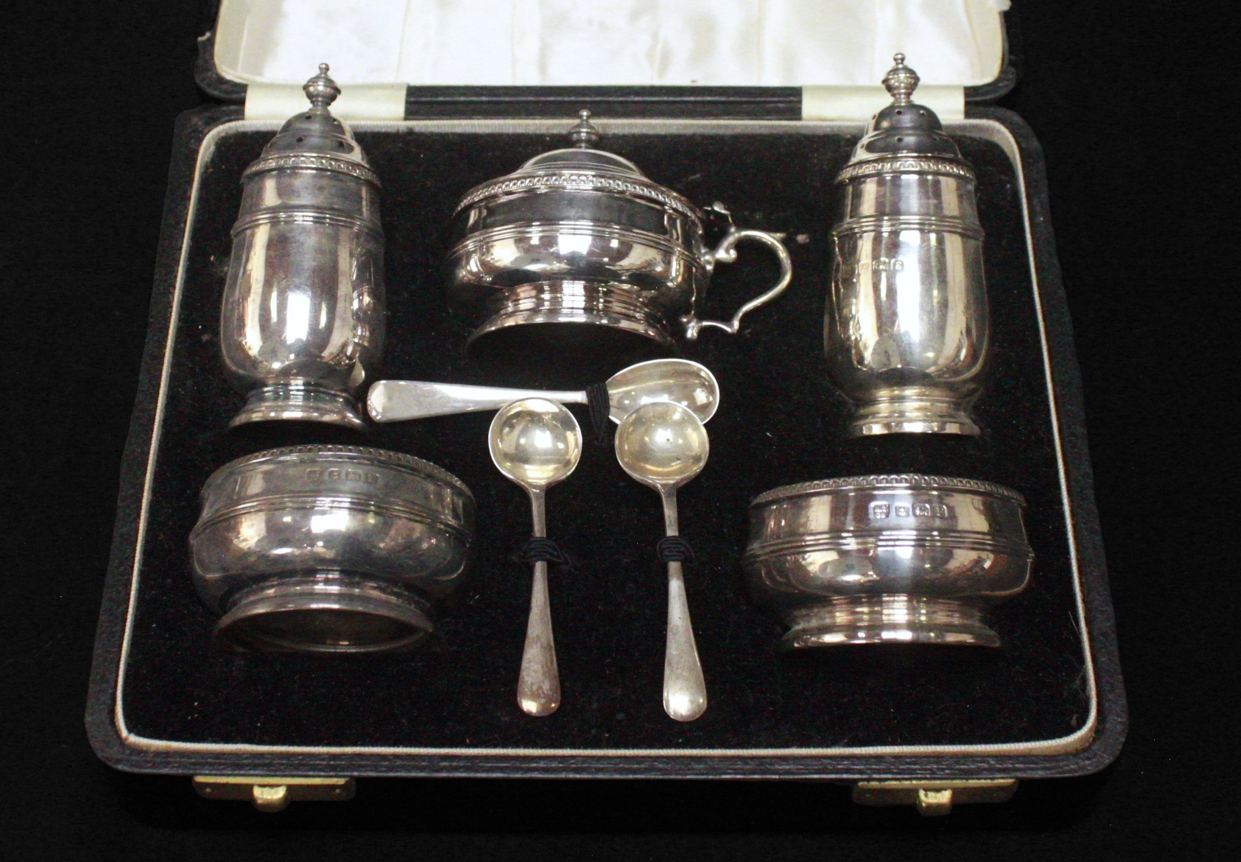 A cased silver cruet set by Northern Goldsmiths & Co, comprising two salt cellars, two