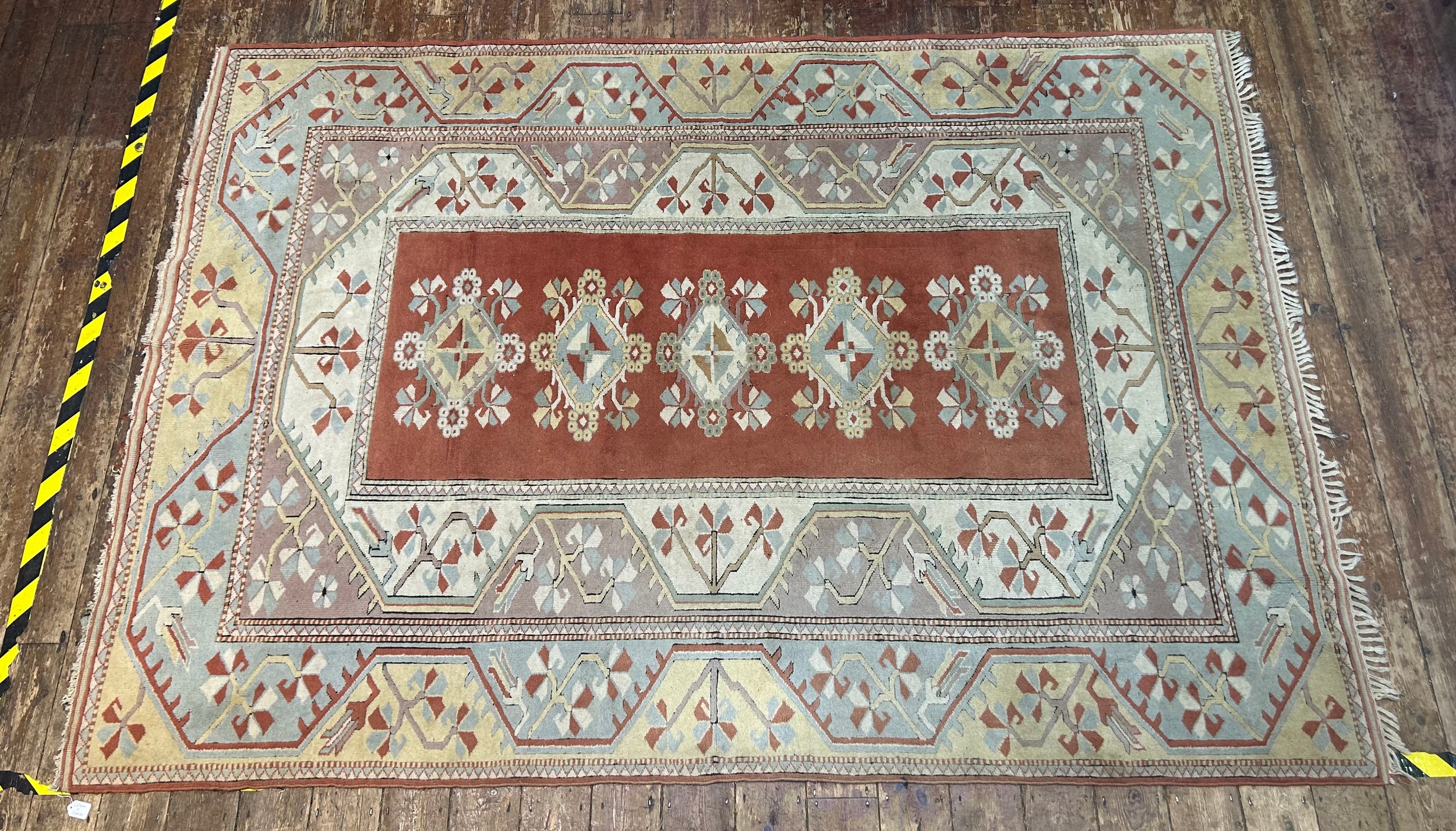 A hand-knotted Caucasian large wool rug, worked in brick-red, yellow, duck egg blue and neutral