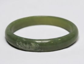 A Chinese Spinach Jade bangle, with a patch of white marbling, 9.5cm diameter