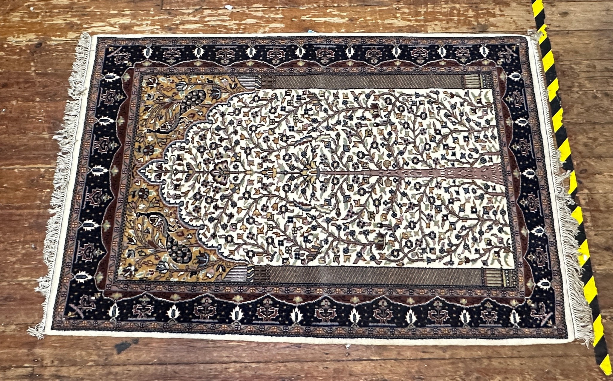 A hand-knotted woollen prayer rug worked with tree of life to a beige central ground within blue