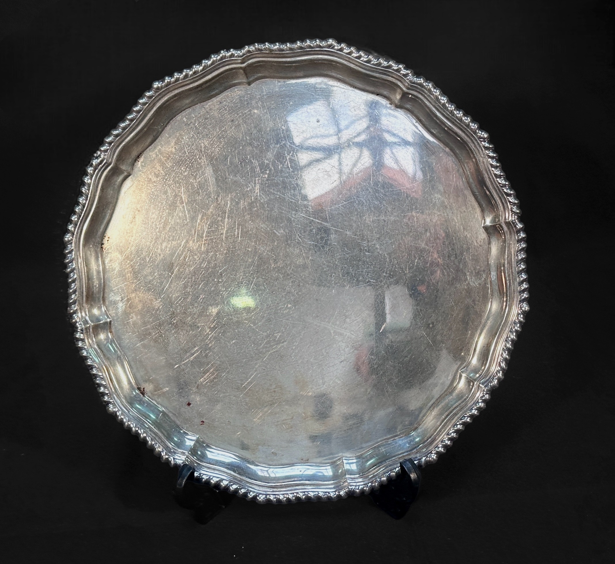 A George III 'style' silver salver, of circular form with gadrooned serpentine rim, raised on