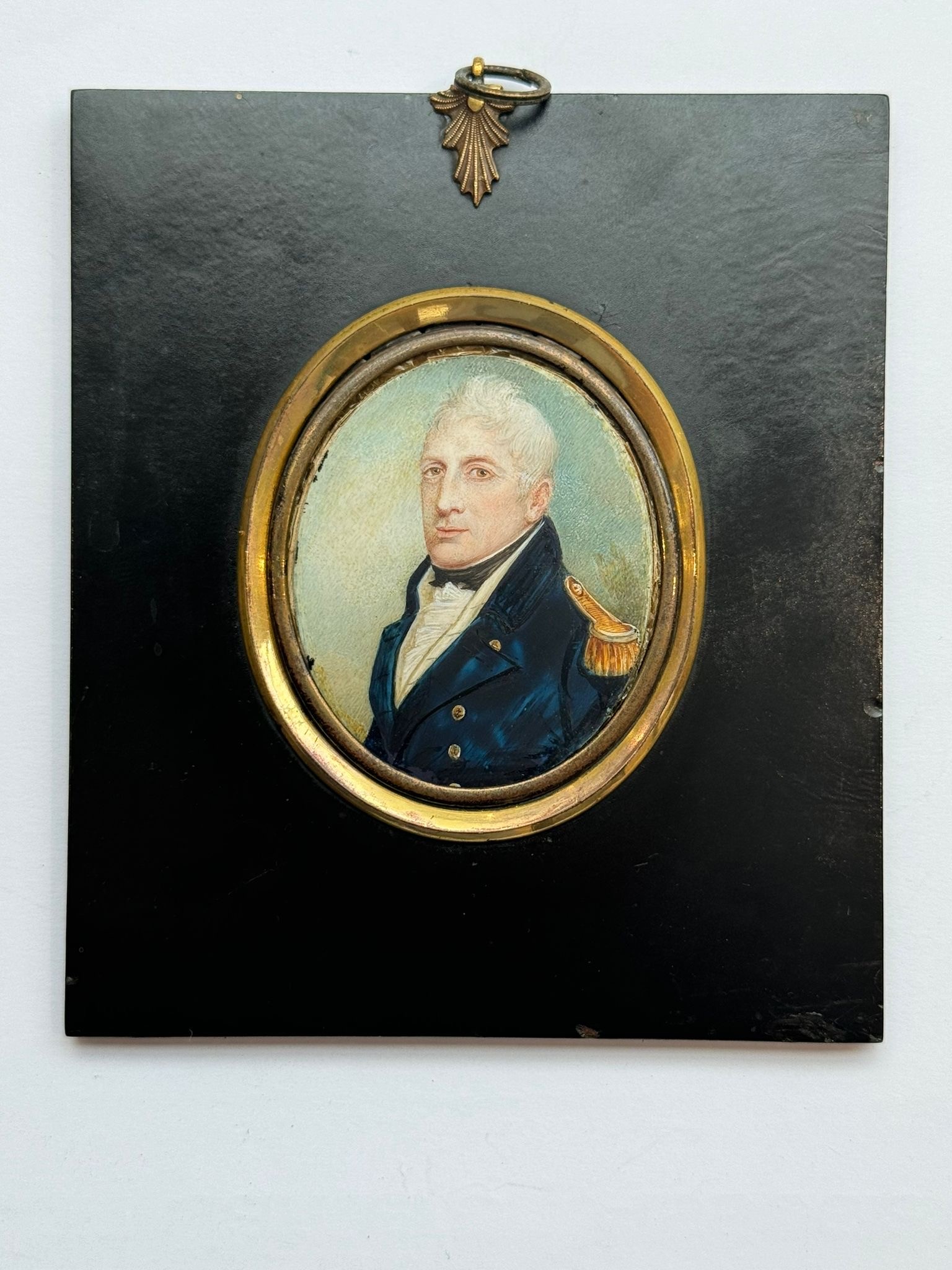 An early 19th century oval portrait miniature of a middle-aged Naval officer, with quiffed grey