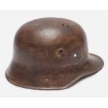 A WWI German M16 Stahlhelm steel combat helmet, lacking liner and chinstrap, splits and holes to
