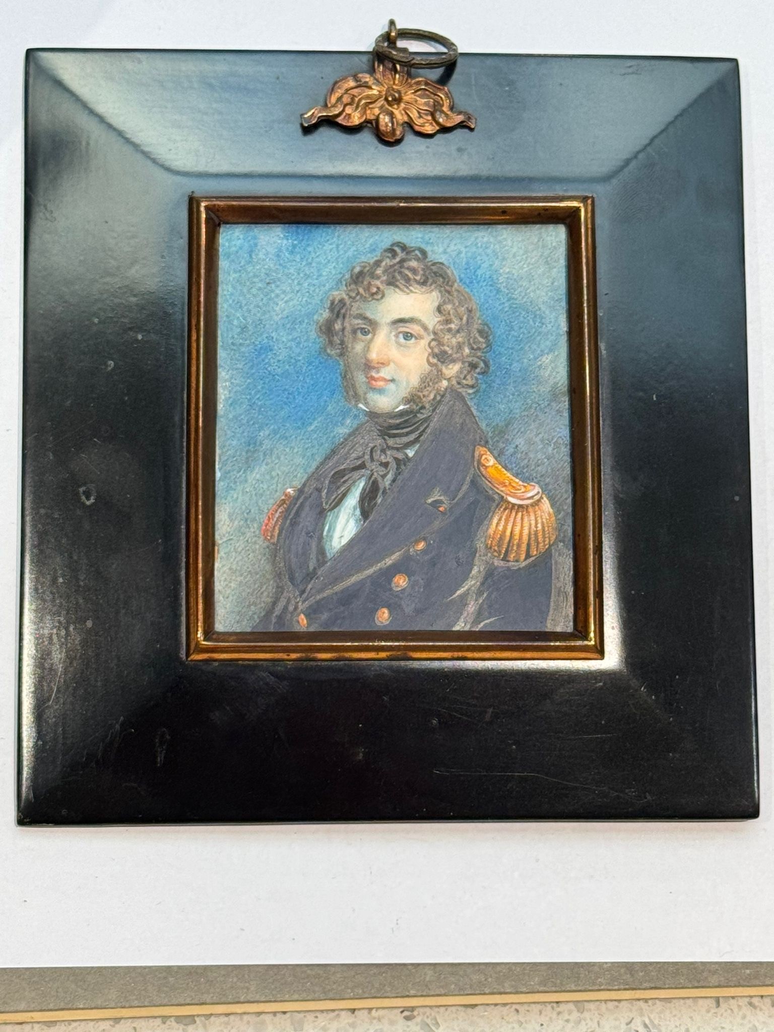 A Mid-19th century portrait miniature of a Naval Commander or Captain, with long curly brown hair