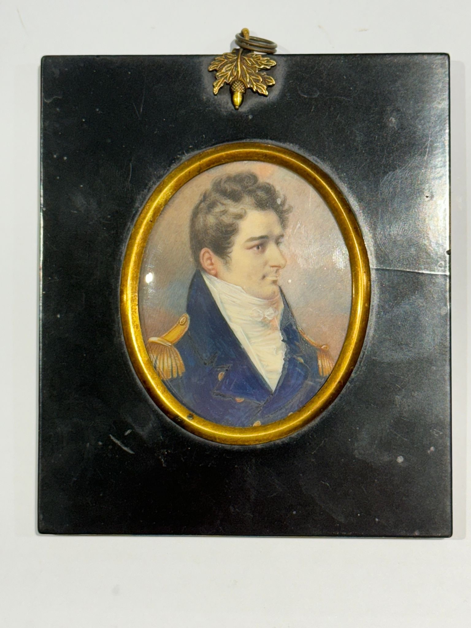 A Mid-19th century oval portrait miniature of a Naval Commander, with brown wavy hair with side
