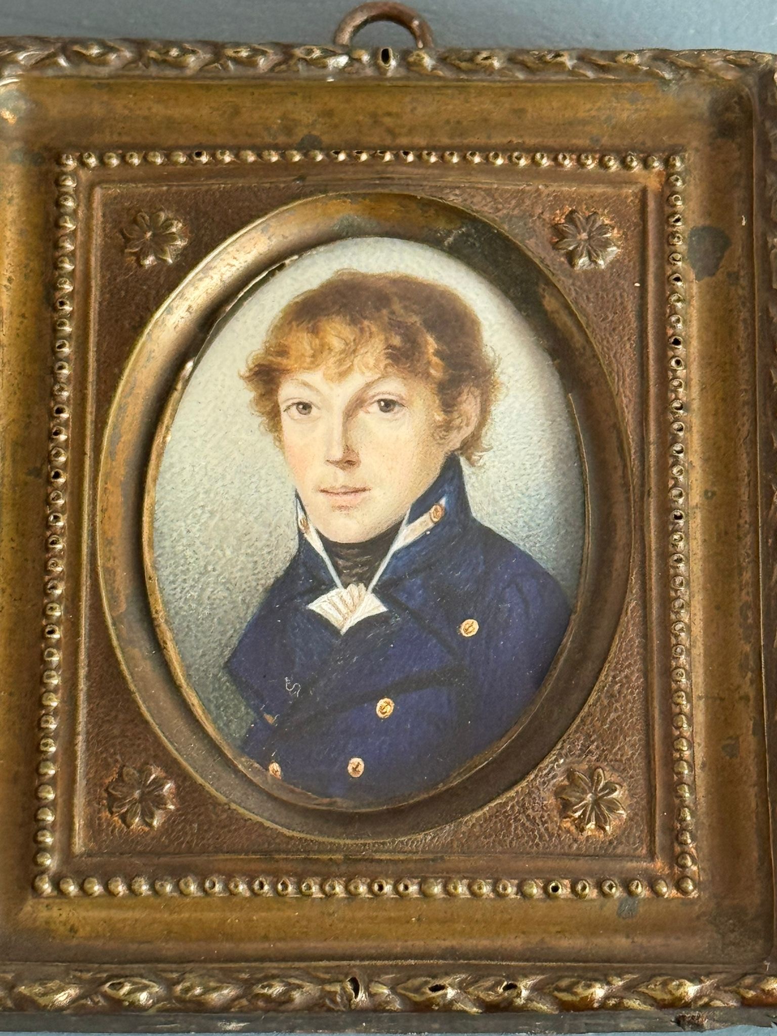 A 19th century oval portrait miniature of a young Naval Midshipman, with light brown long wavy hair,