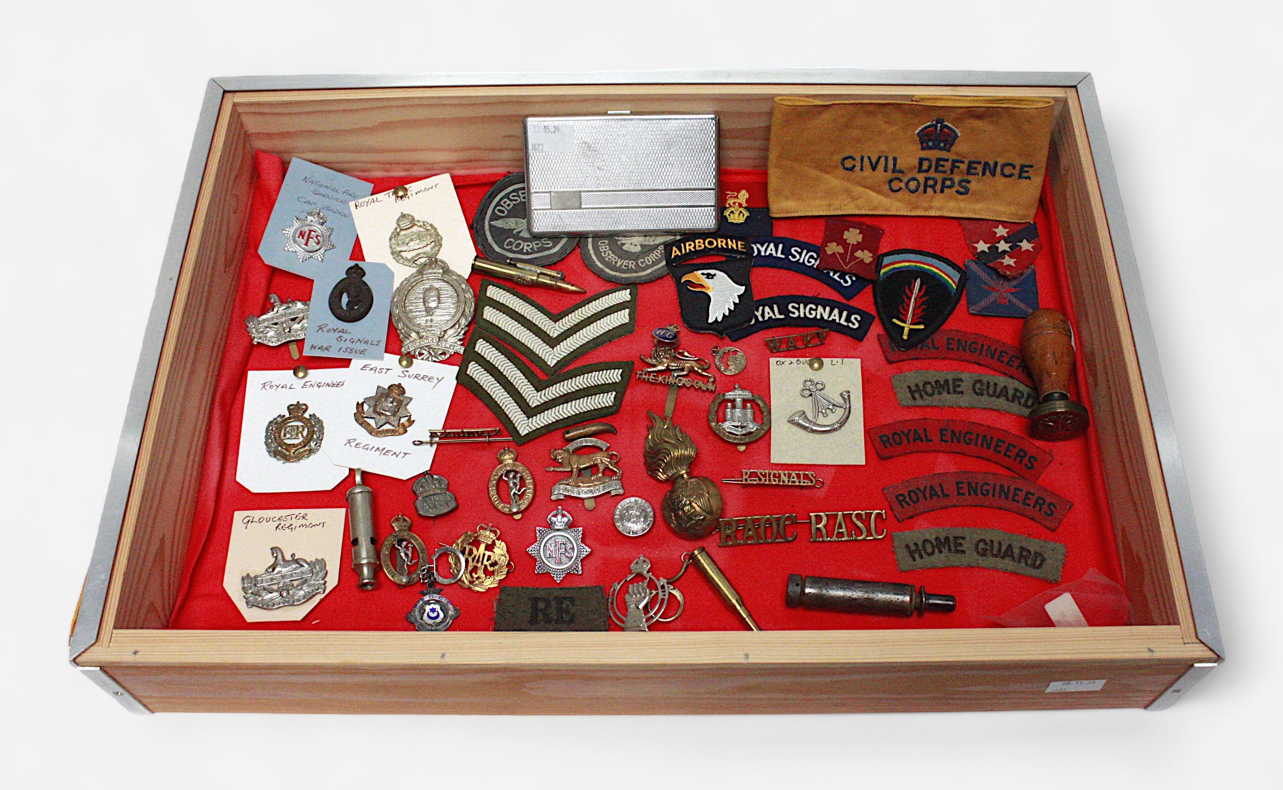 A collection of British military cap badges and shoulder badges etc, together with a WW1 whistle,